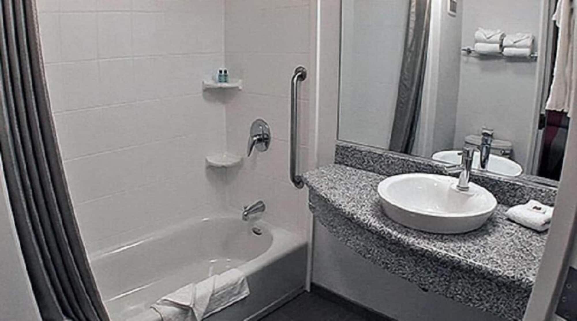 A bathroom with a bathtub, a sink, and a mirror.