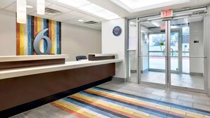 A reception area with a large number '6' sign, a clock, and an exit door. - Motel 6 Marble Falls, TX (Marble Falls)