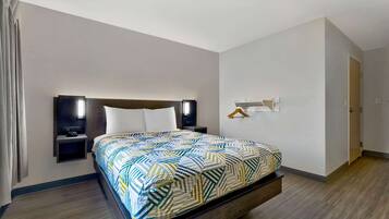 Una habitación de hotel con cama, mesitas de noche, televisor y perchero.