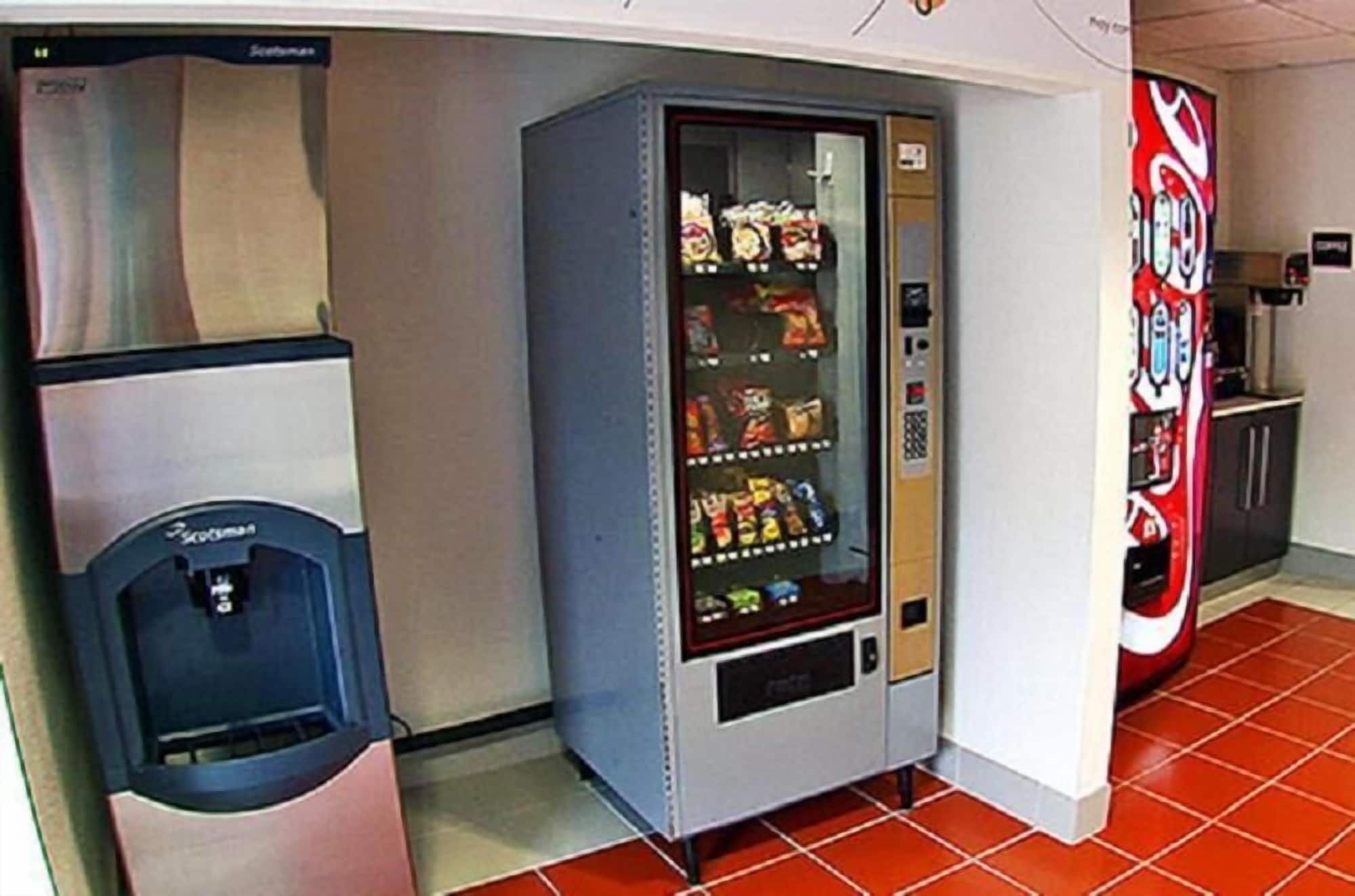 A vending machine with snacks and a drink dispenser in a commercial setting.