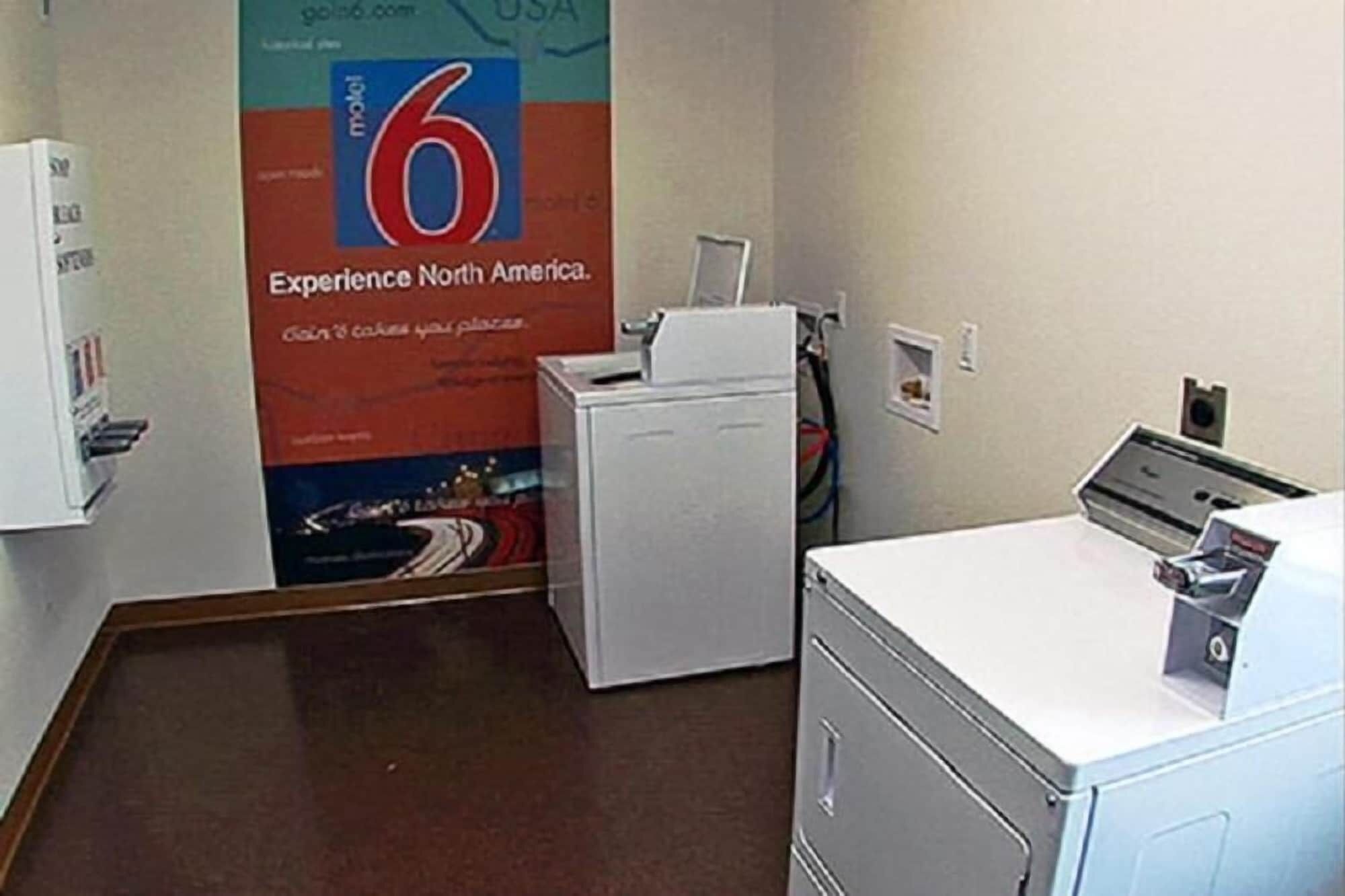 A laundry room with a washing machine, dryer, and a large poster advertising a travel experience.