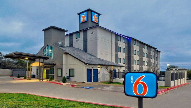 A motel with a modern design, featuring a prominent '6' sign, a satellite dish, and a flat roof. - Motel 6 Marble Falls, TX (Marble Falls)