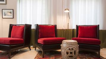 Une pièce comprenant trois chaises noires avec des coussins rouges, une petite table ronde et un lampadaire.