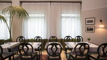A dining area with a long table, multiple chairs, and a large plant.