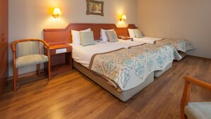 Habitación de hotel con dos camas, suelo de madera y dos lámparas fijadas a la pared.
