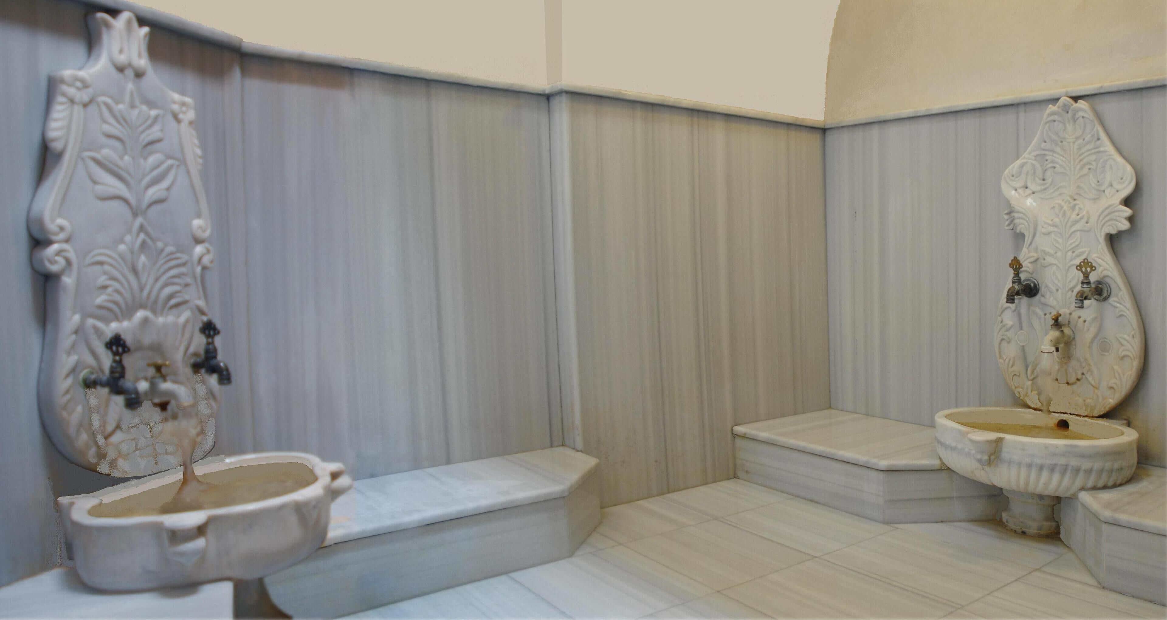 A bathroom with a toilet, a sink, and a decorative wall panel.