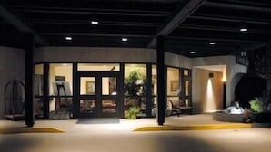 A modern building entrance with glass doors, a concrete floor, and a yellow curb. - The Inn at Houndslake (Aiken)