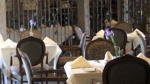 A restaurant interior with multiple tables and chairs, some with floral centerpieces. - The Inn at Houndslake (Aiken)