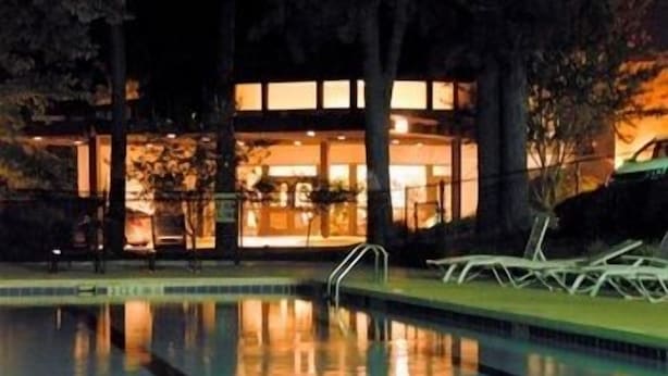 A swimming pool with a clear view of a building in the background. - The Inn at Houndslake (Aiken)