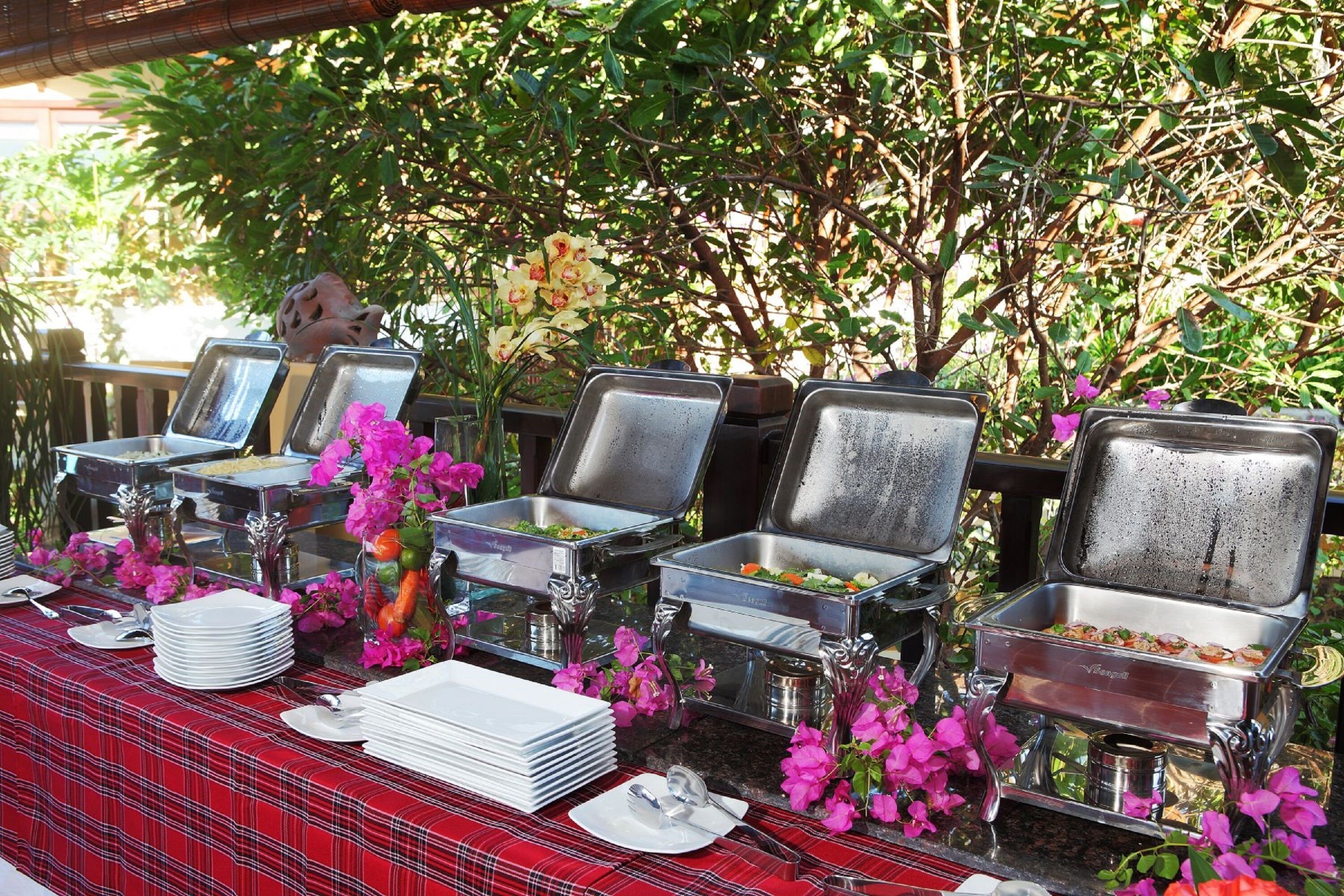 A buffet setup with multiple serving trays and a red checkered tablecloth.