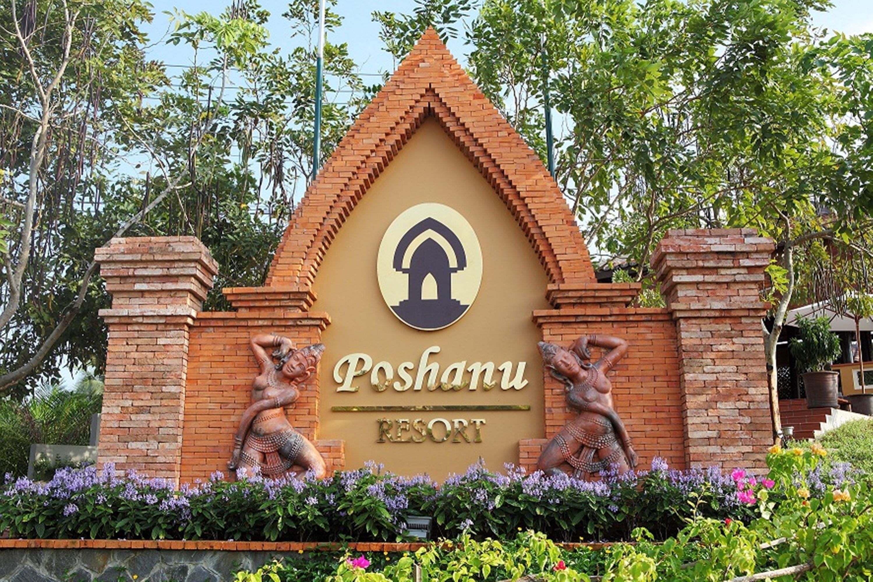 A sign for Poshanu Resort with a triangular roof and two statues on either side.