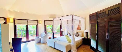 A spacious bedroom with a four-poster bed, a ceiling fan, and a view of the outdoors.