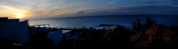 Vista costera con atardecer, edificios y cielo despejado.