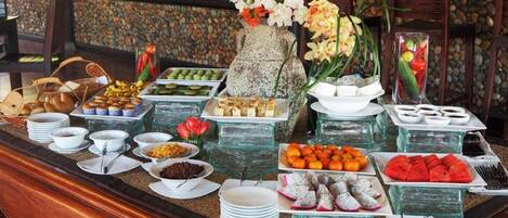 A buffet with various food items and a decorative vase with flowers.