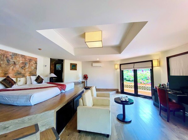 Habitación de hotel con cama, escritorio, silla, mesita y televisor.