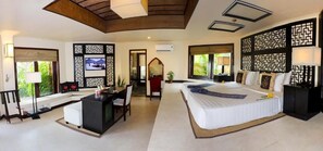 A spacious bedroom with a large bed, a desk, and a view of greenery outside. - Poshanu Resort (Phan Thiet)