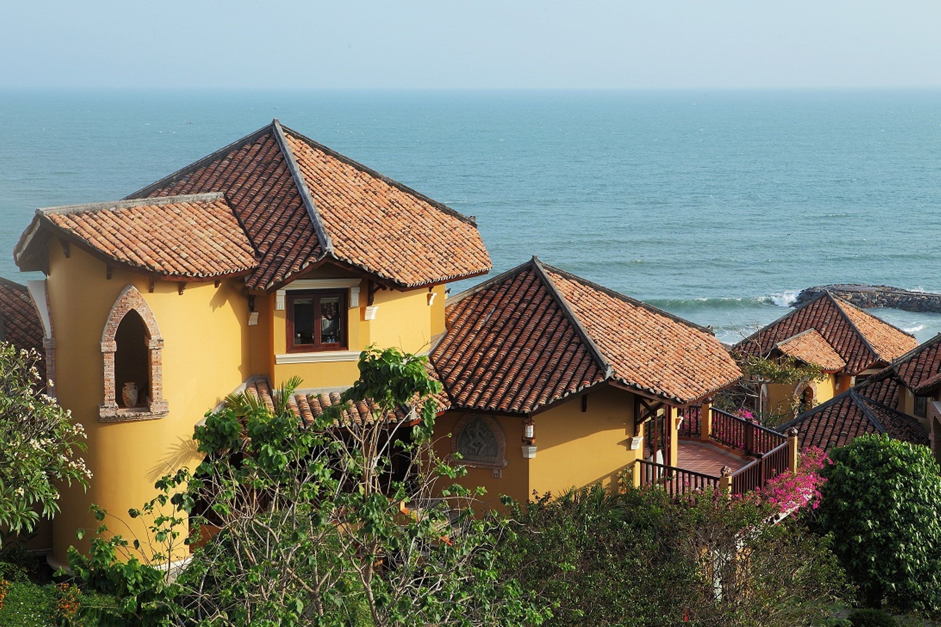 Un edificio costero con tejados de terracota, un balcón y vista al mar.