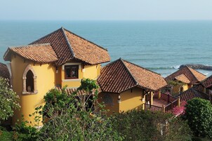 Un edificio costero con tejados de terracota, un balcón y vista al mar.