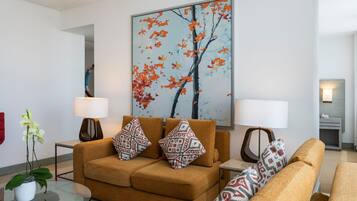 Een moderne woonkamer met een bank, twee bijzettafeltjes, een vloerlamp en een groot abstract schilderij.