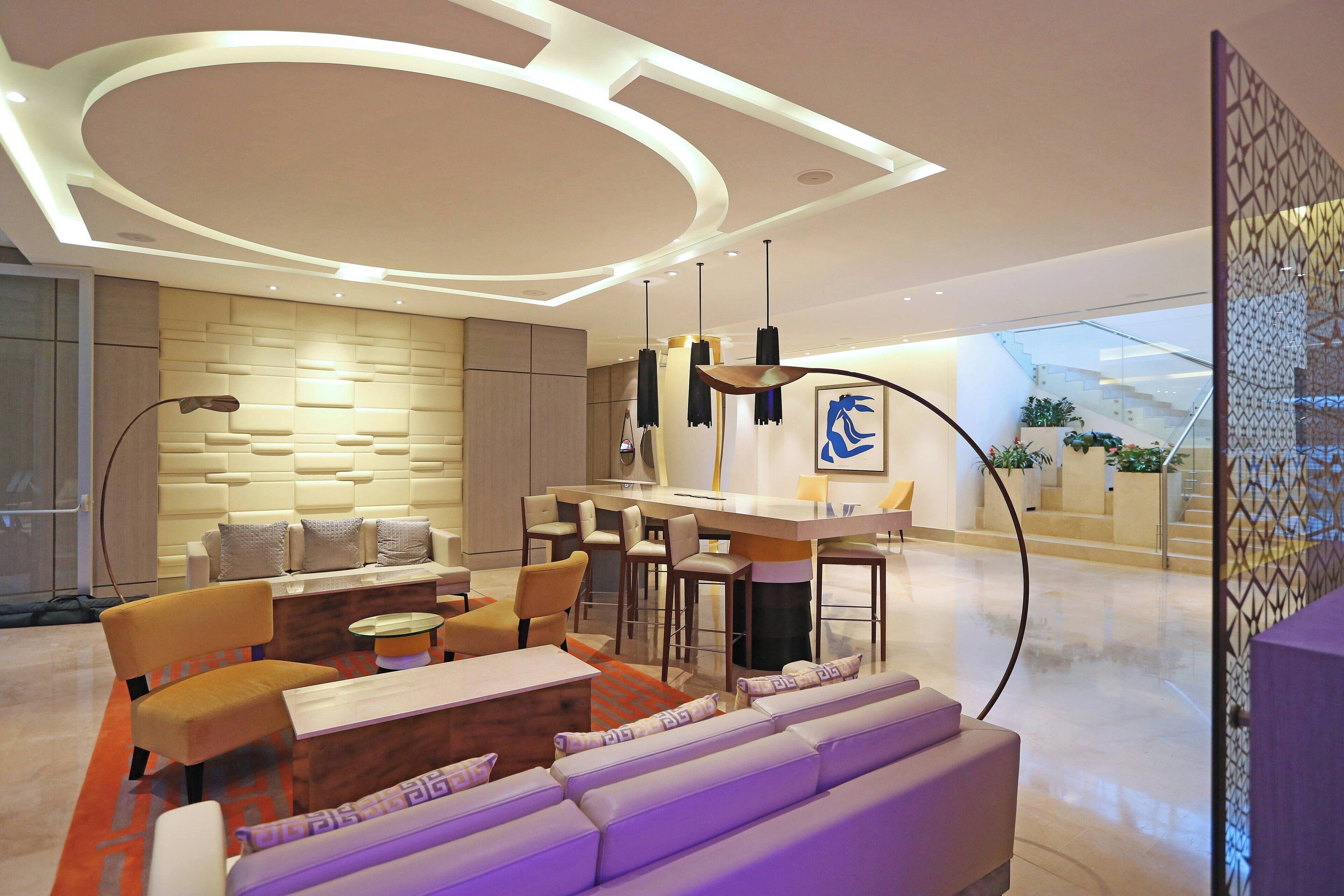 A modern living room with a sofa, chairs, a coffee table, and a dining area with a bar.