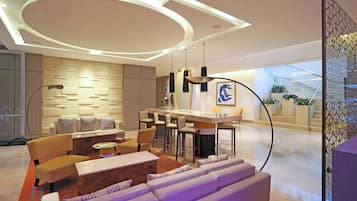 A modern living room with a sofa, chairs, a coffee table, and a dining area with a bar.