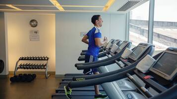 A gym with treadmills, a dumbbell rack, and a large window with a view of the outside.