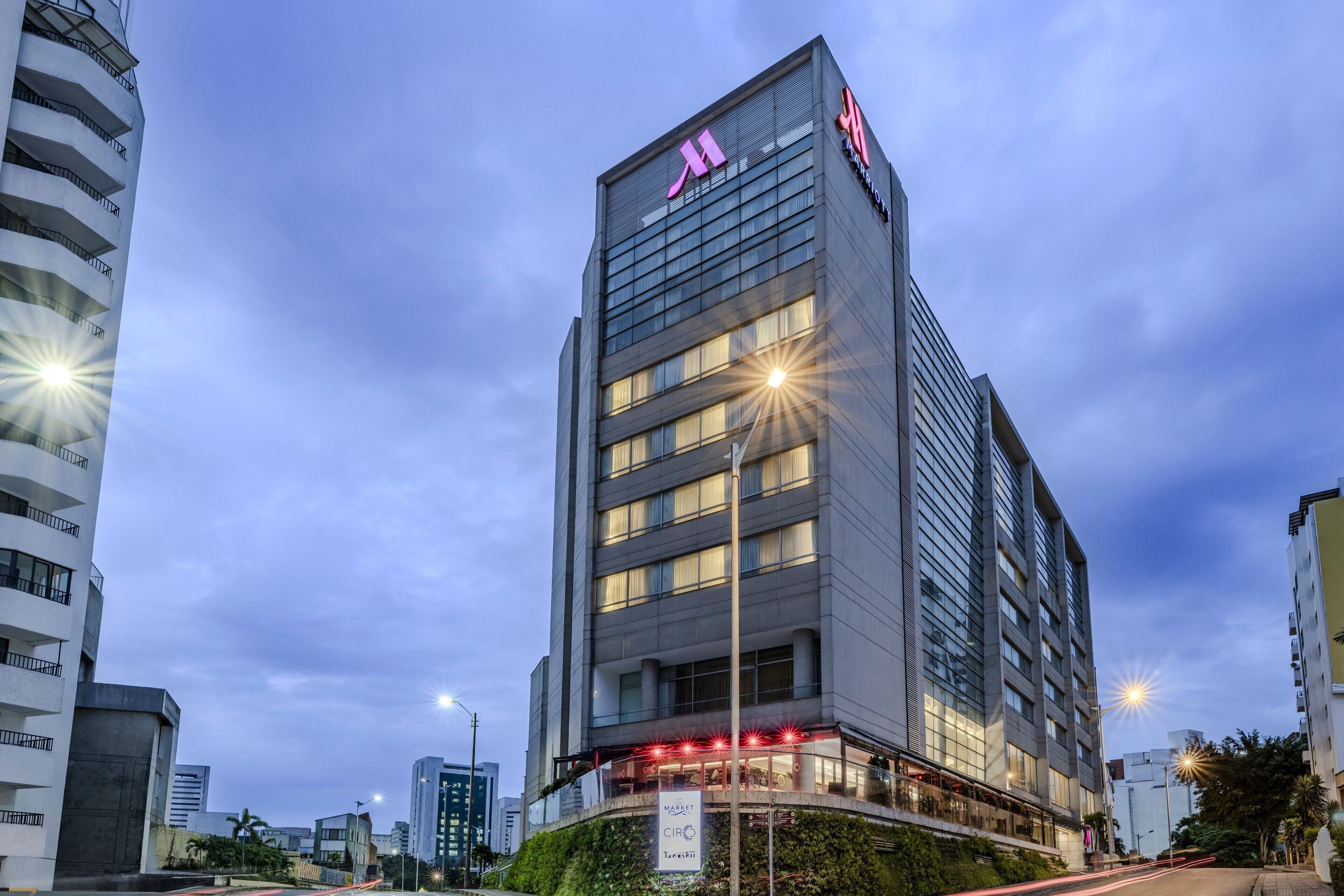 Un hotel moderno con una entrada destacada, varios pisos y fachada bien iluminada.