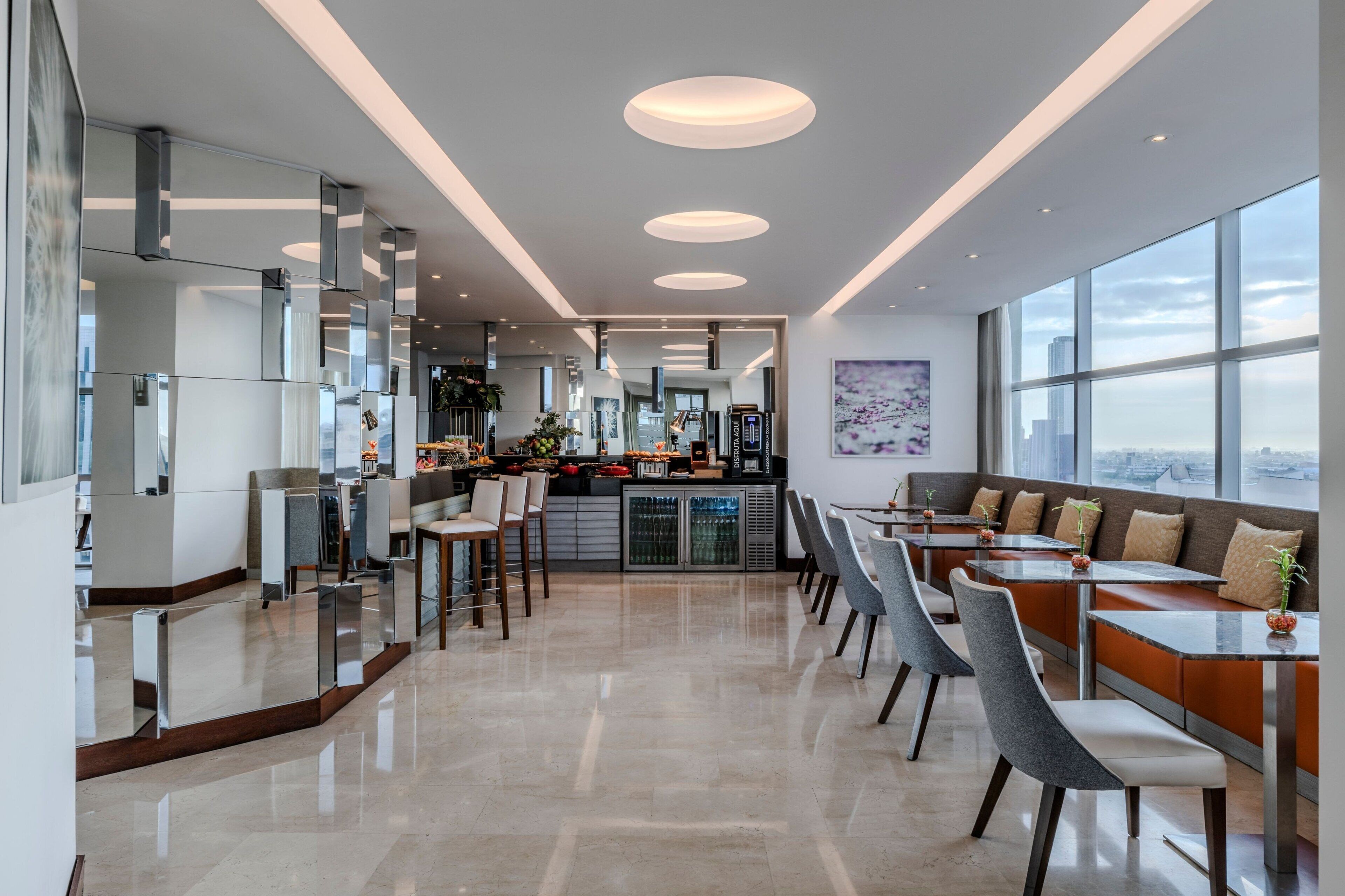 A modern kitchen with a central island, bar area, and seating with a city view.
