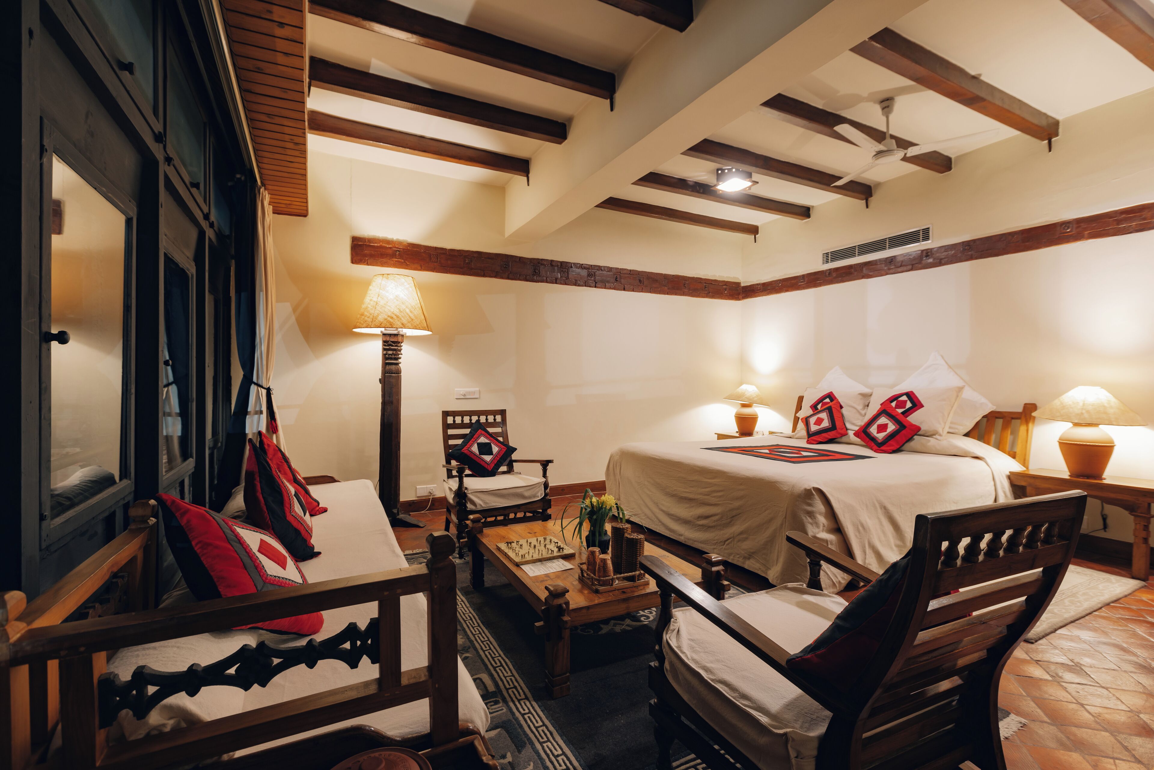 A cozy room with a bed, two chairs, a small table, and a lamp.