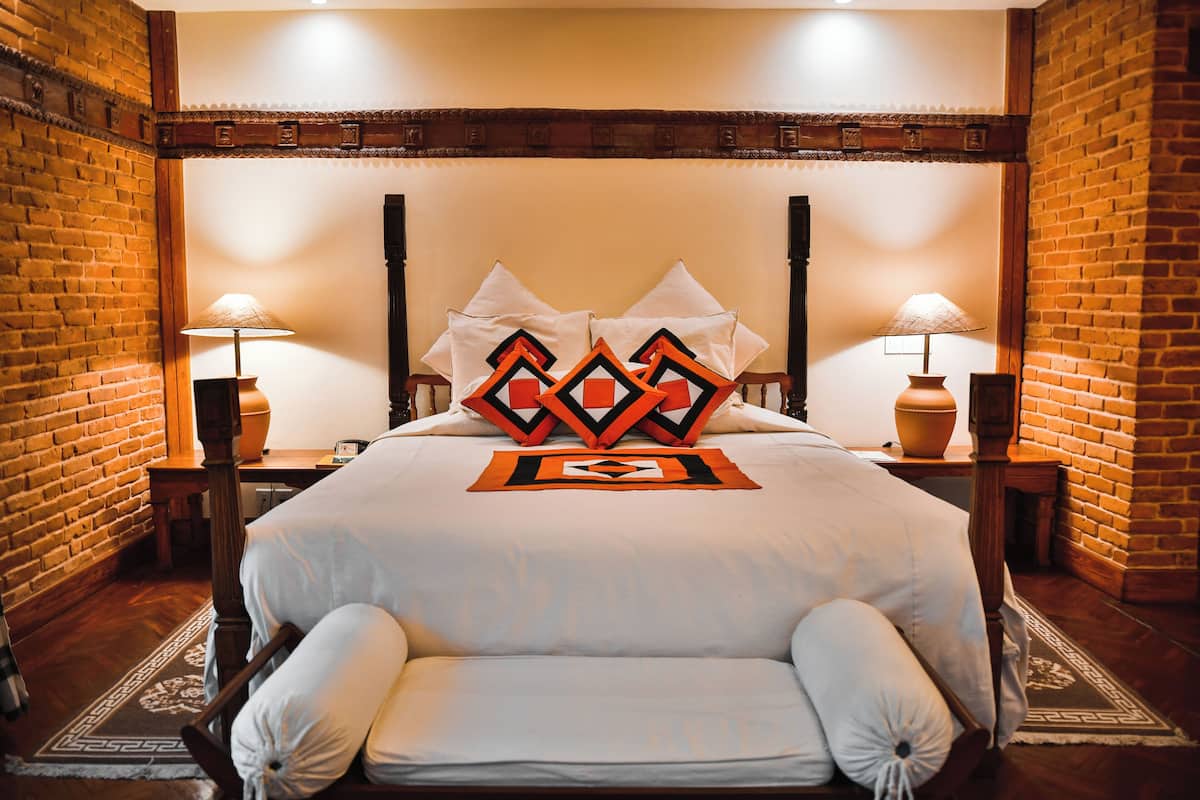 A hotel room with a large bed, two nightstands, and a brick wall.