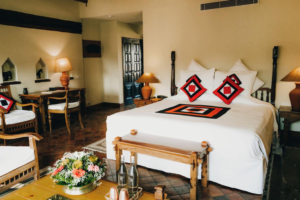 A hotel room with a large bed, wooden furniture, and a small table with a vase of flowers.