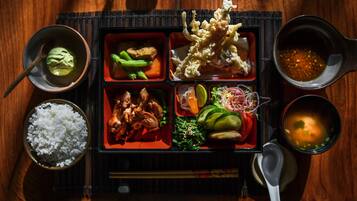 A meal with various dishes in separate compartments, including rice, vegetables, and meat.