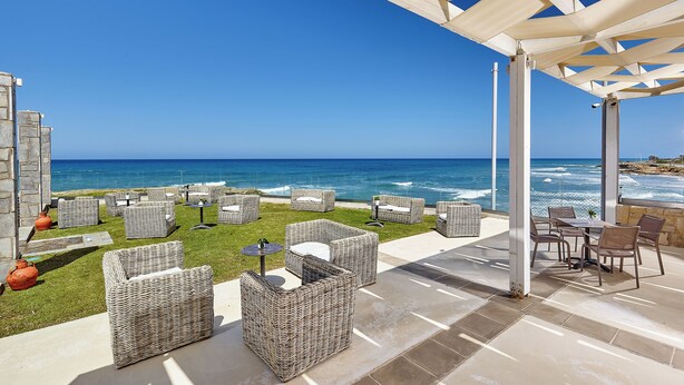 An outdoor patio with wicker furniture and a view of the ocean. - St. Constantin Beach Hotel and Spa (Hersonissos)