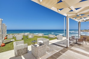 An outdoor patio with wicker furniture and a view of the ocean.