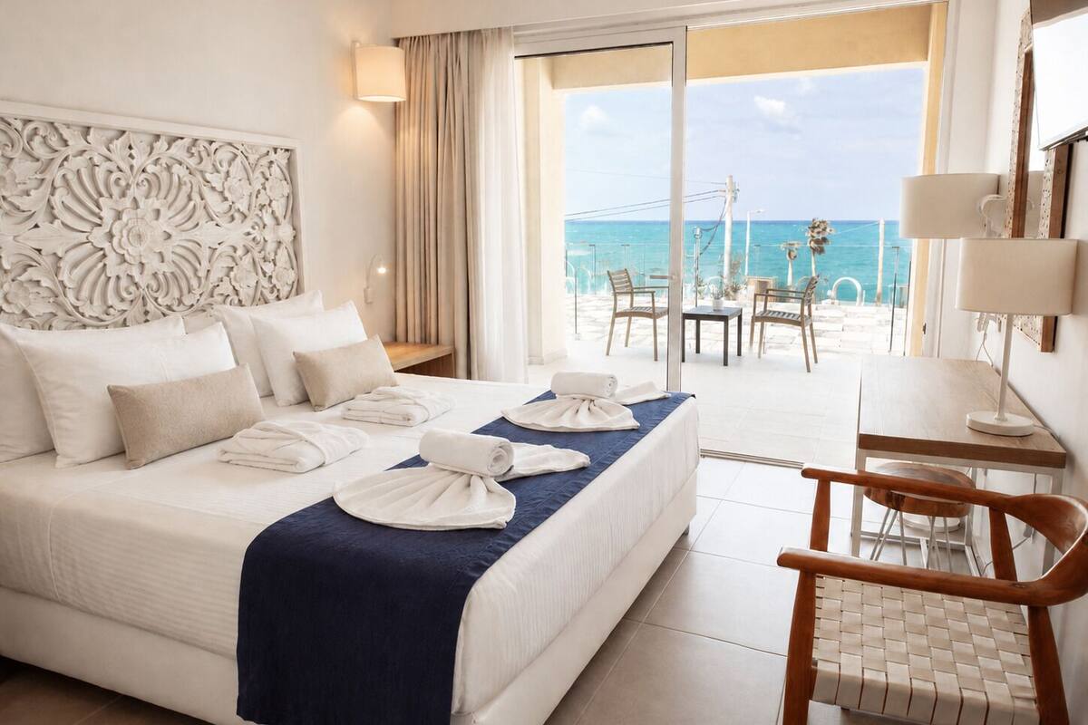 A hotel room with a bed, a desk, and a view of the beach.