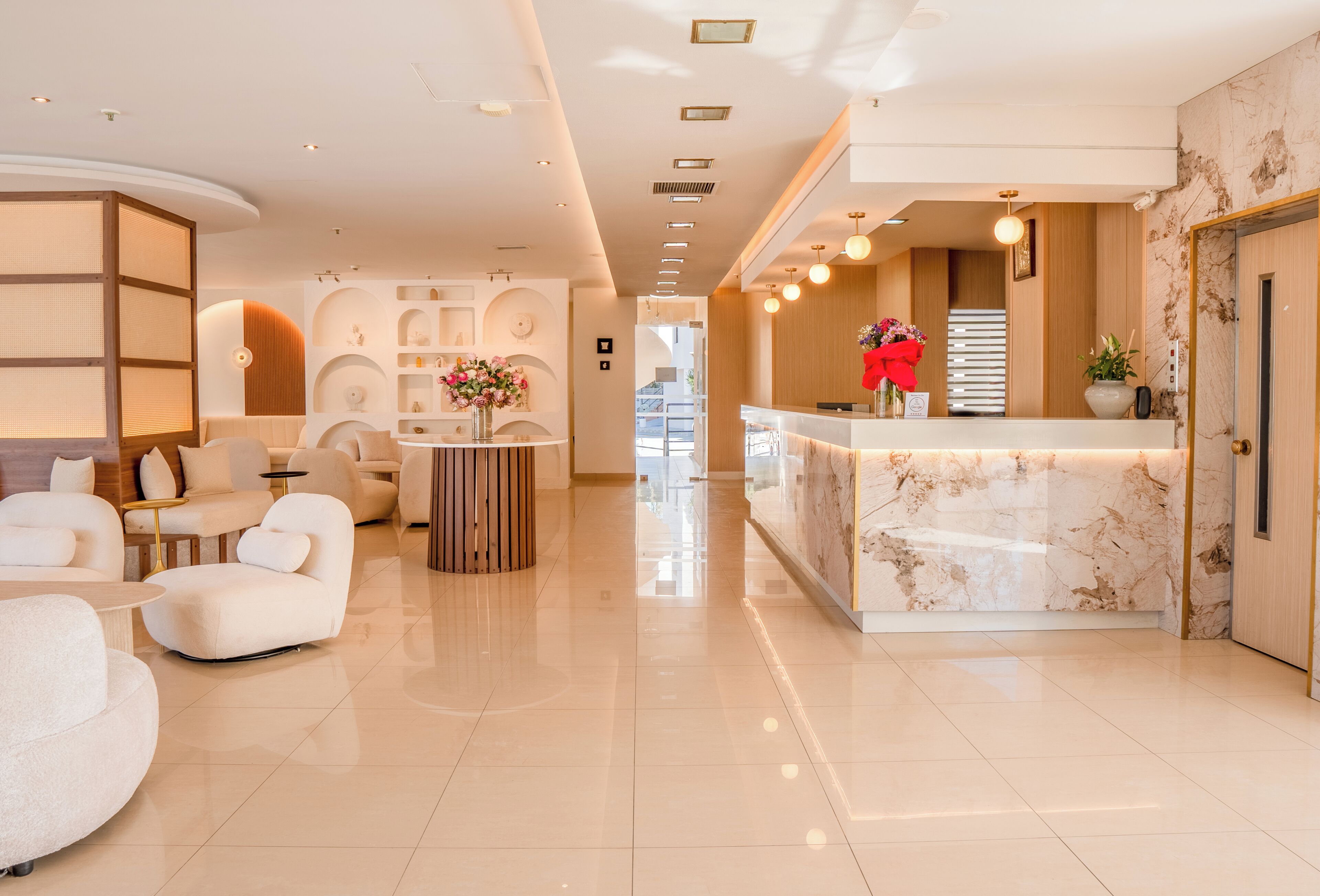A modern hotel lobby with a reception desk, seating area, and decorative elements.