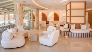 A modern lounge area with plush seating, a glass wall, and a wooden partition. - St. Constantin Beach Hotel and Spa (Hersonissos)