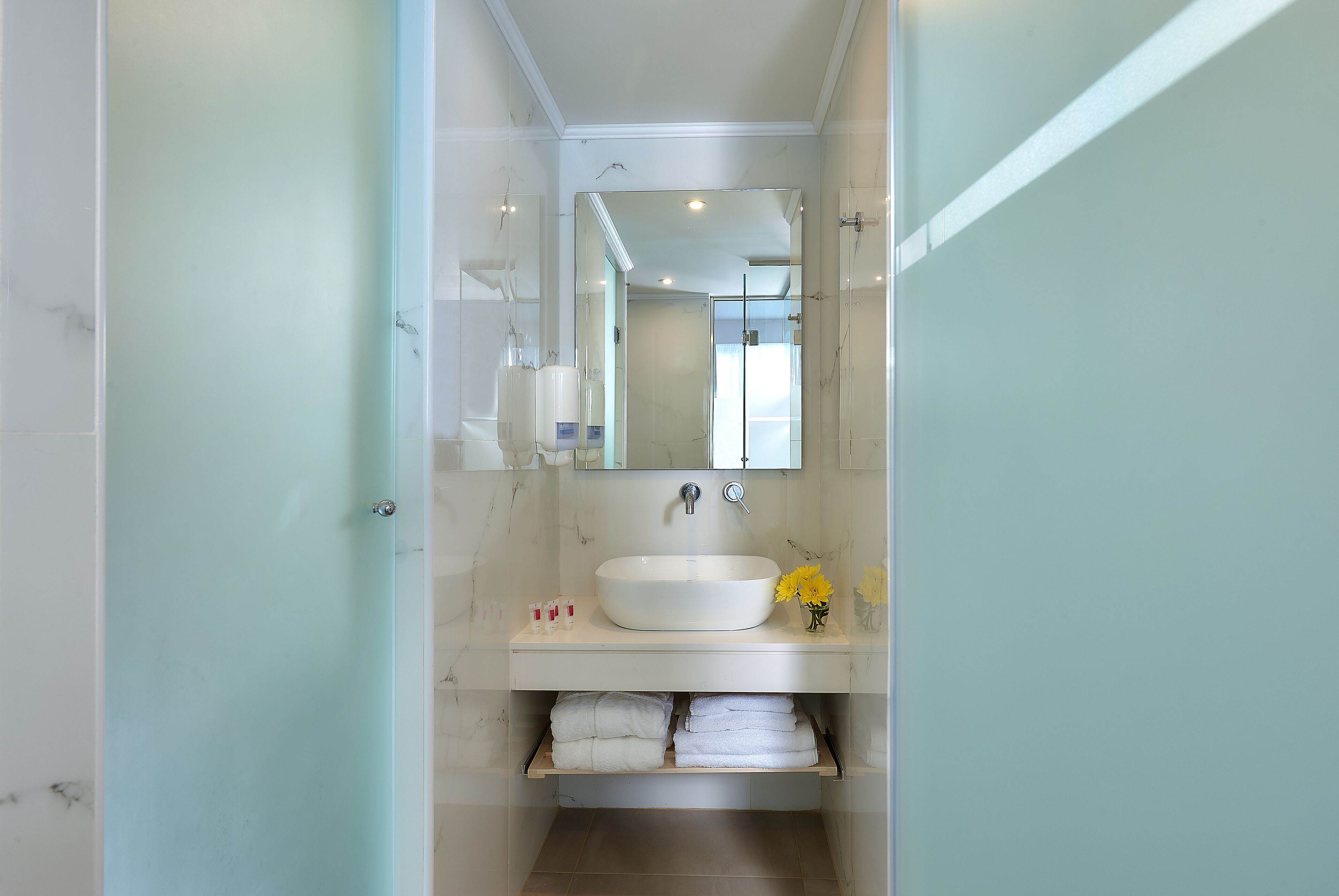 A bathroom with a white sink, a mirror, and a towel rack.