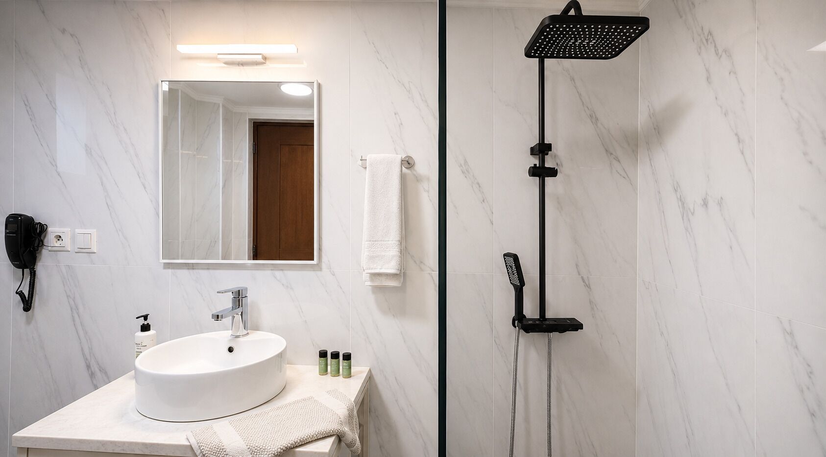 Une salle de bain avec un lavabo blanc, un miroir, un porte-serviettes, une douchette à main et un sèche-cheveux.