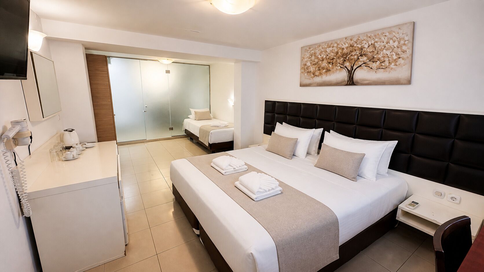 A hotel room with a bed, bedside table, and a mirror.