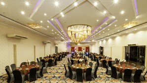 A large banquet hall with round tables, chairs, and a central stage. - Heritage Hotel (Anuradhapura)