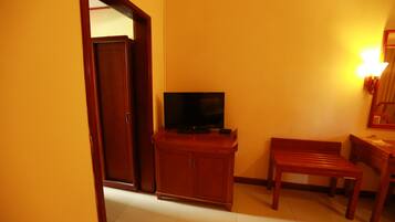 Una habitación con un armario de madera, un televisor, un banco y una puerta.