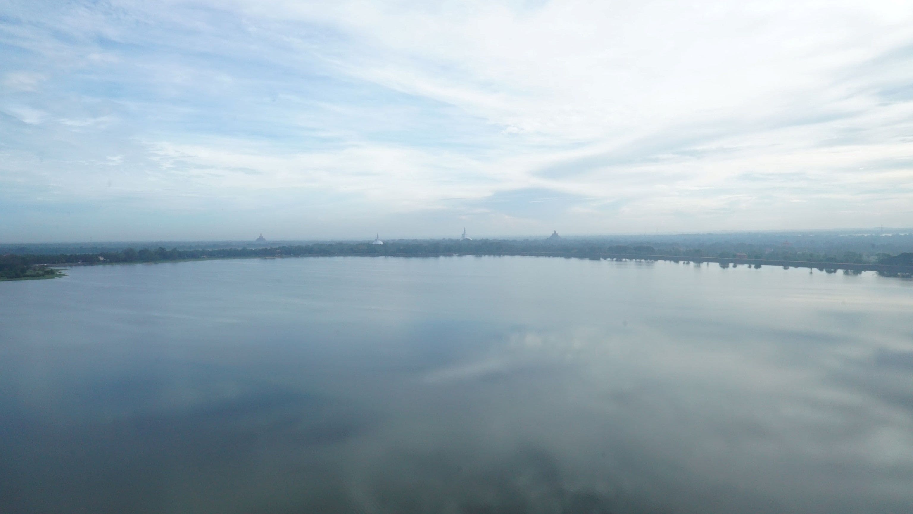 Una masa de agua tranquila con una costa distante y un cielo despejado.