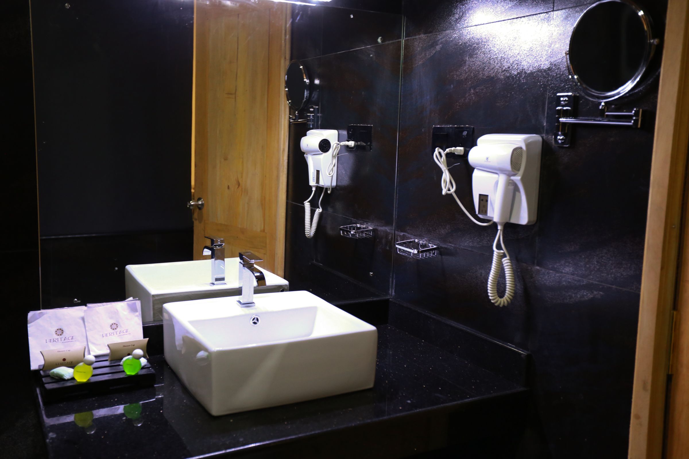 A bathroom with two sinks, a hairdryer, and a mirror.