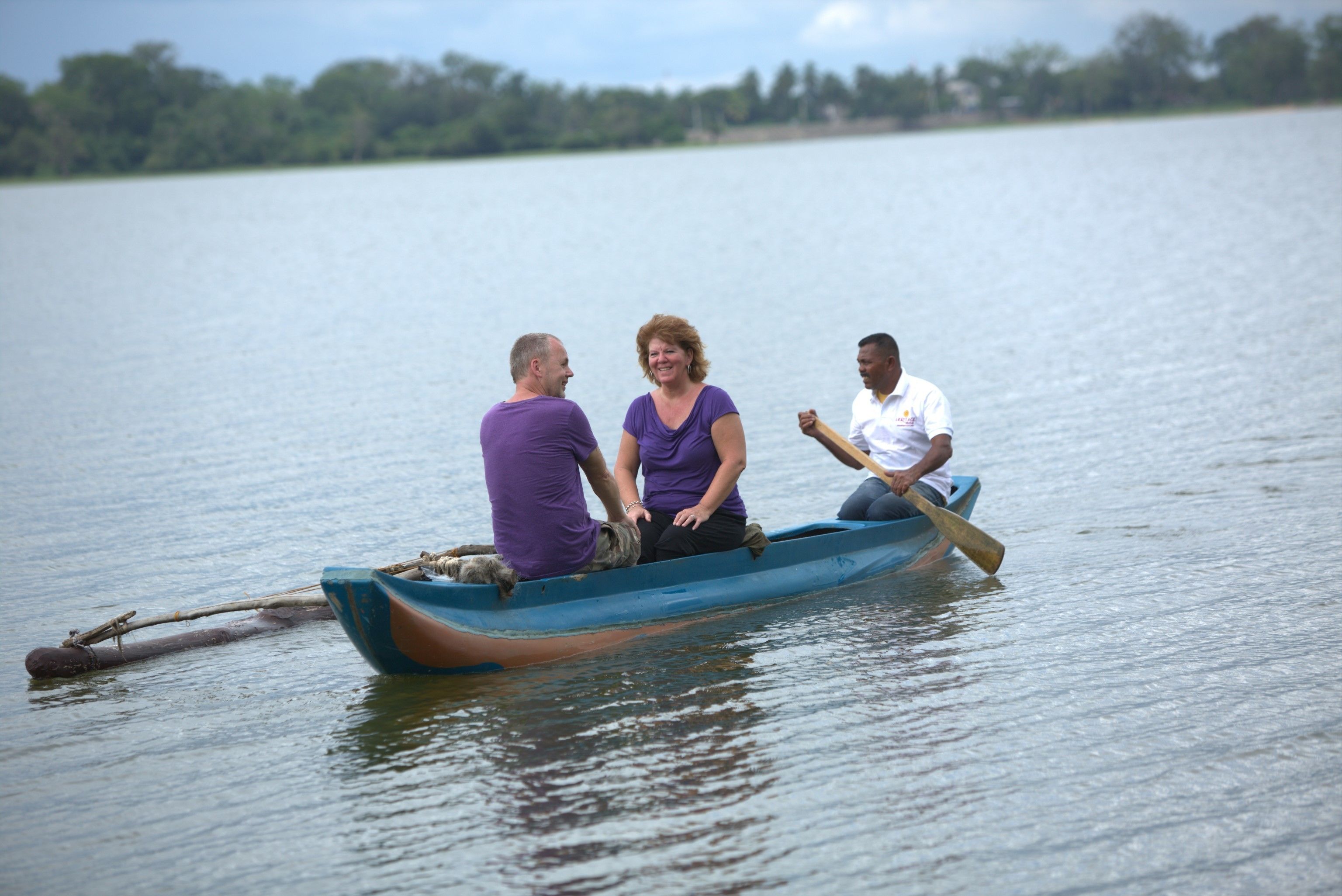 Tres personas en un bote pequeño en un lago tranquilo.