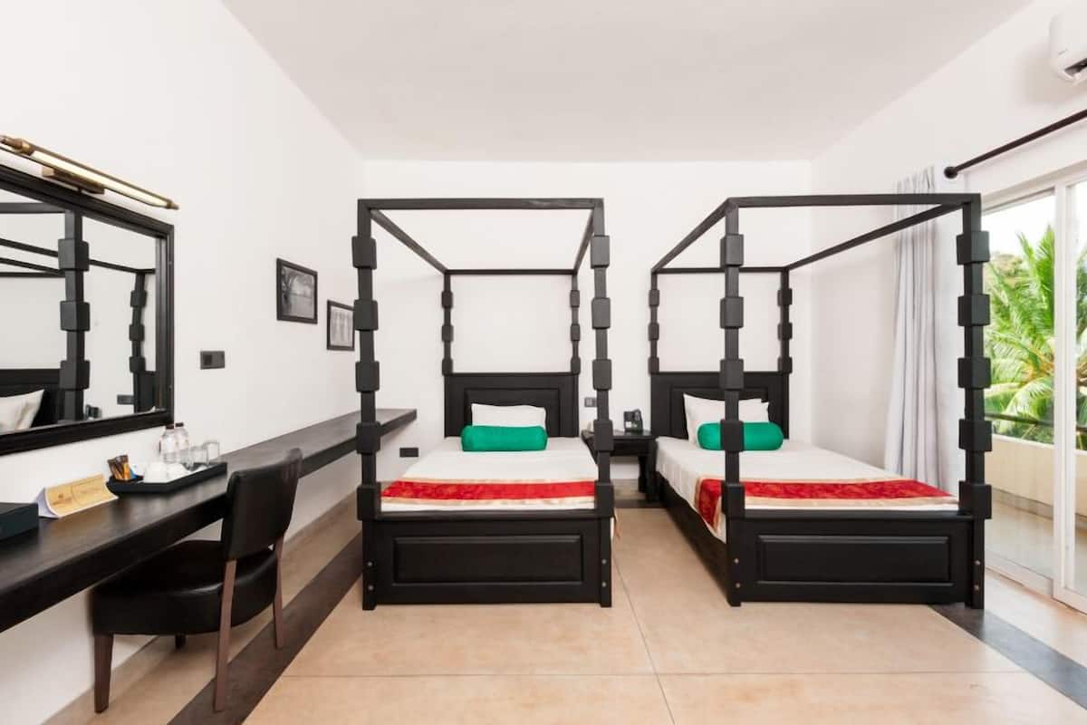 A room with three black four-poster beds, a desk, and a chair.