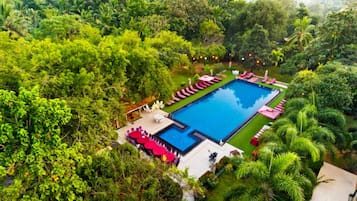 Relax by the serene pool surrounded by lush greenery and comfortable lounge chairs.