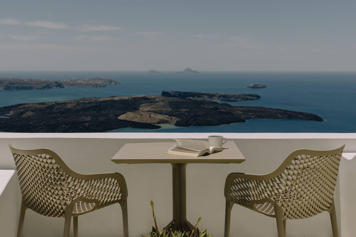 A balcony with two chairs, a table, and an open book.
