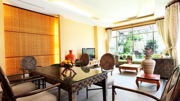 A dining area with a glass-top table, wicker chairs, and a television.