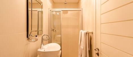 A modern bathroom with a large white sink, a glass shower enclosure, and a towel rack.